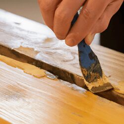 applying wood filler to cracks and chips with a putty knife